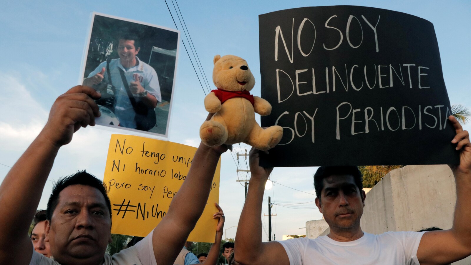 Un homme brandit une photo d'un cameraman assassiné à Cancun.
