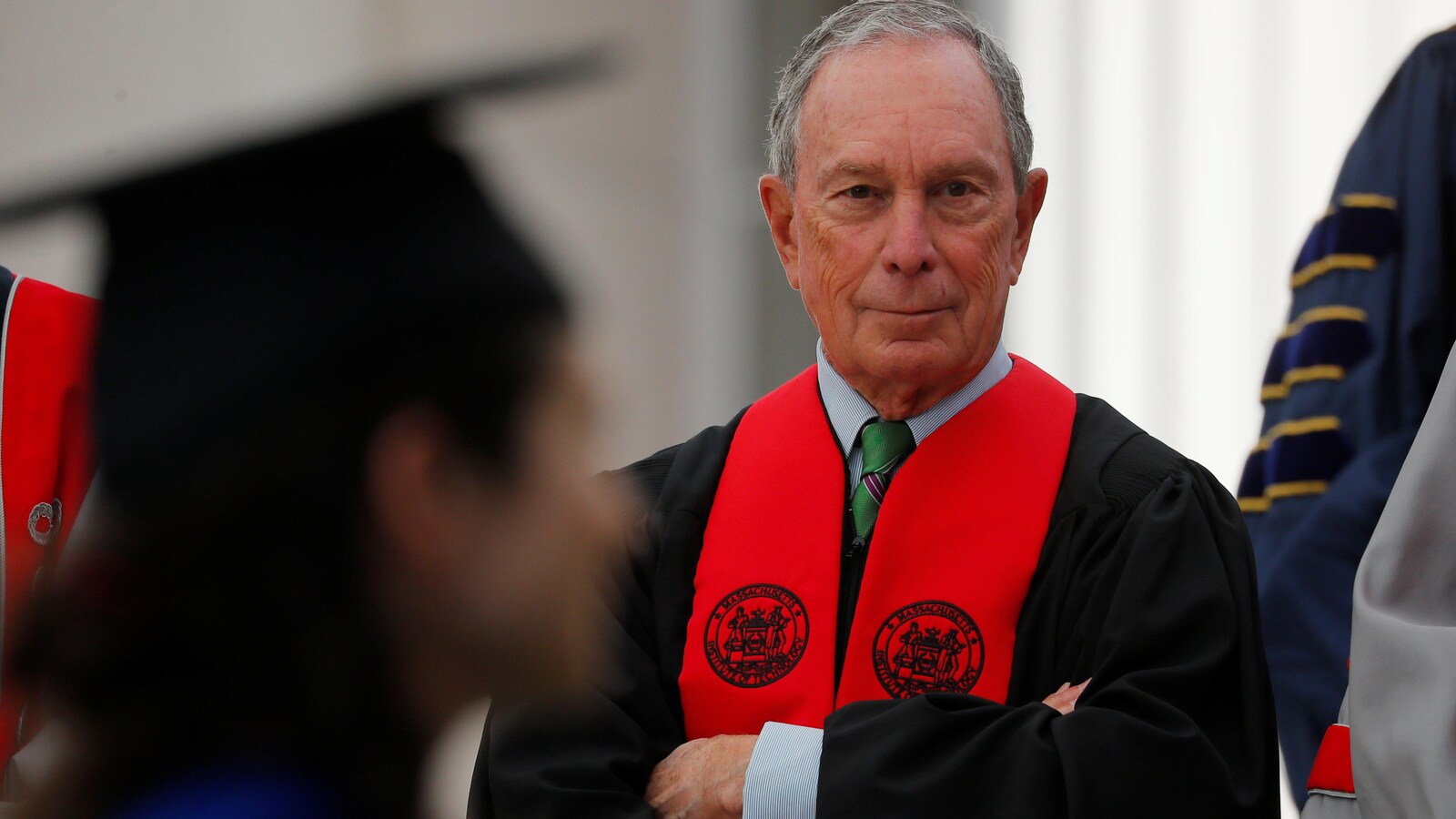 Michael Bloomberg est vêtu d'une toge du MIT et il observe les jeunes étudiants.