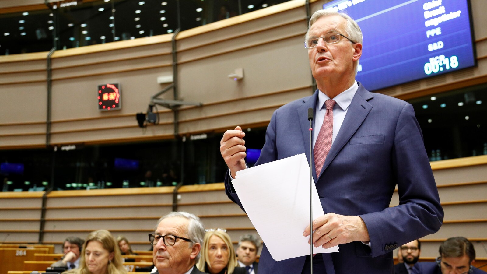 Un homme parle debout dans une grande salle.