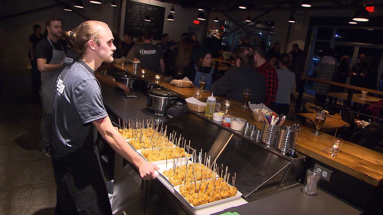 Un serveur dans une brasserie avec des hors d'oeuvre pour la dégustation de La Compagnie, une nouvelle bière artisanale à Sept-Îles