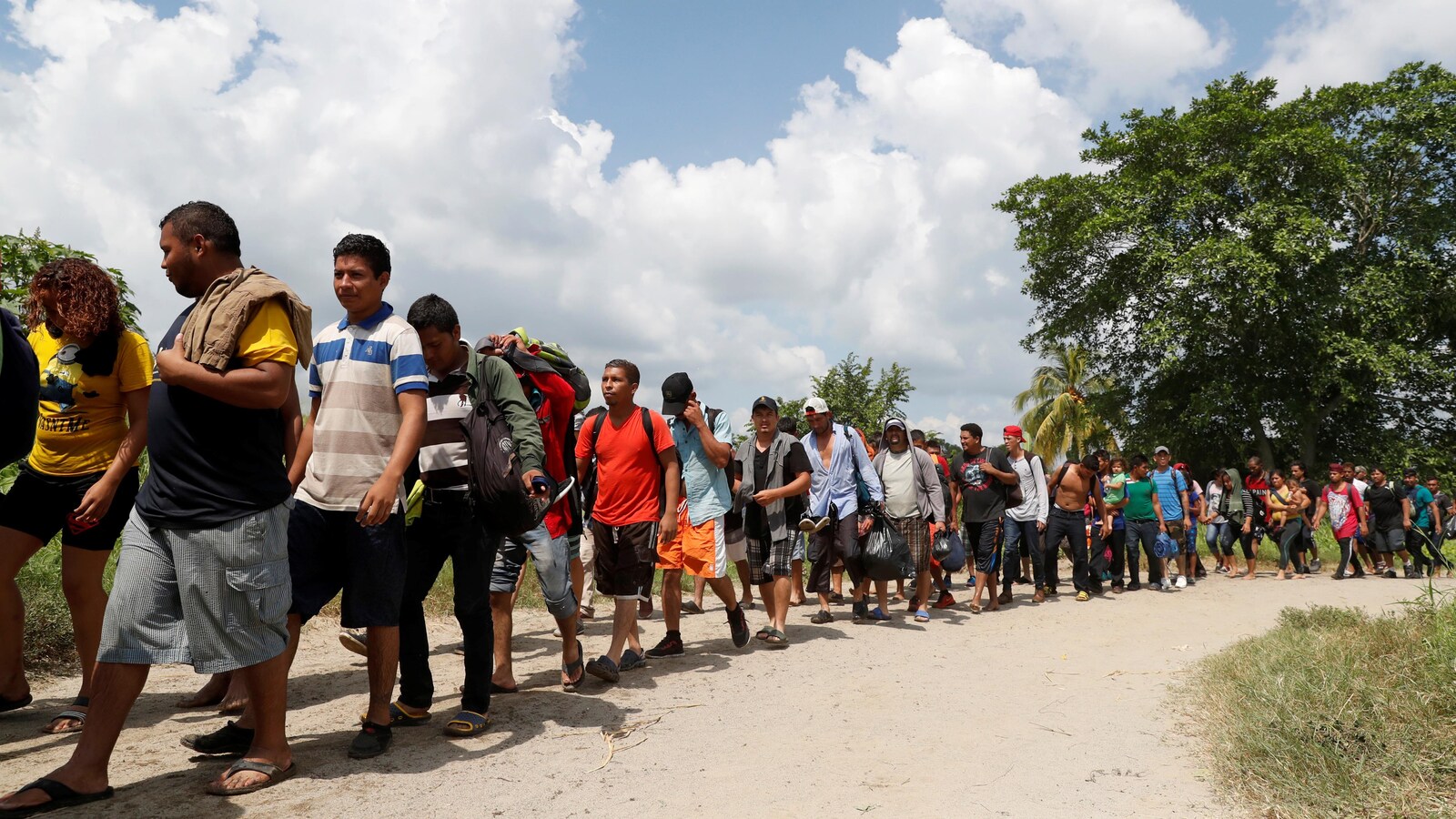 Une longue file de personnes marchent sous le soleil.