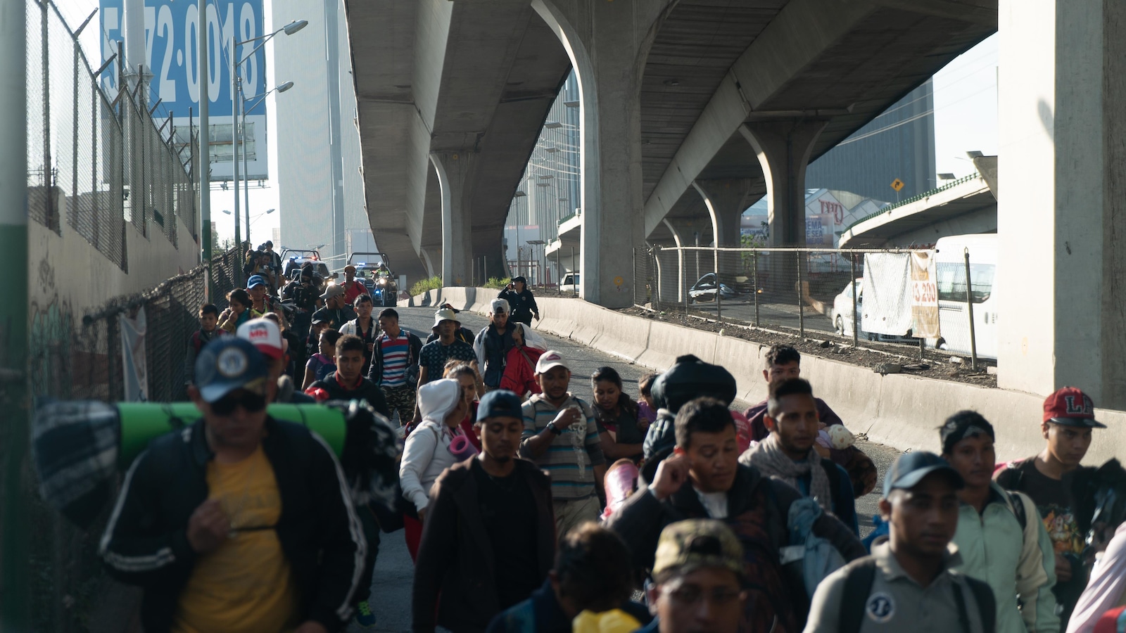 Des migrants marchent sous l'autoroute.