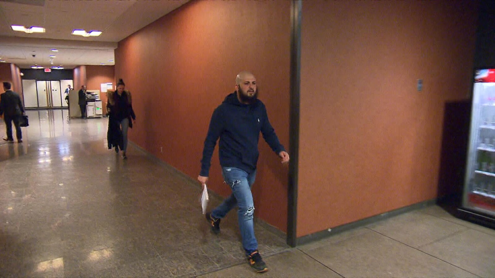 Mohamed Taleb tenant des feuilles entre ses mains dans un couloir du palais de justice.