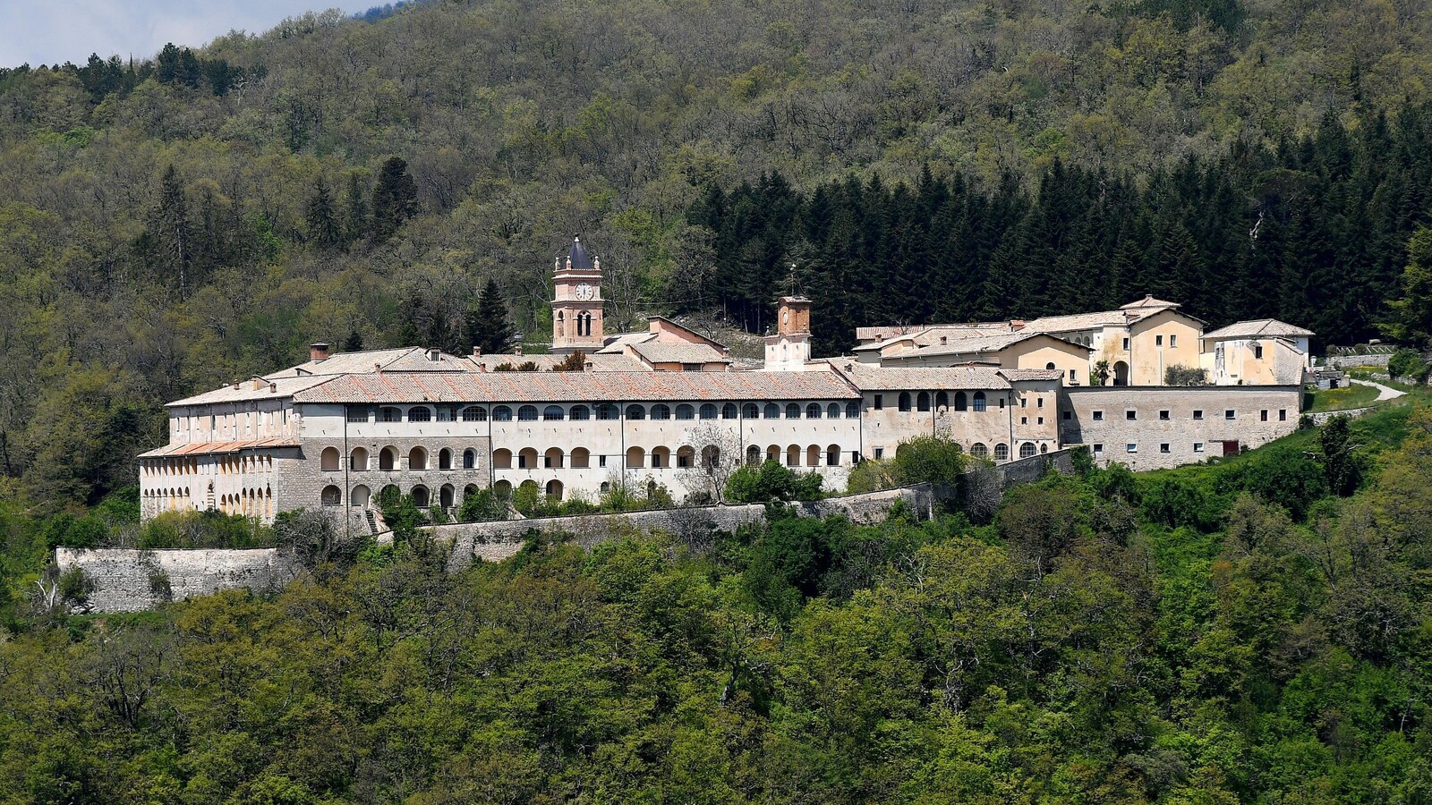Vue sur un bâtiment ancien situé en montagne et entouré d'arbres en Italie.