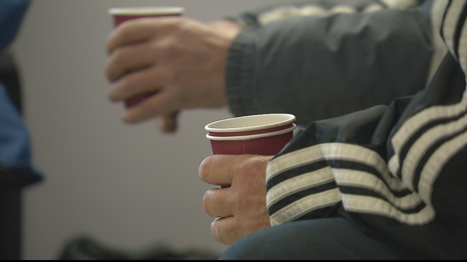 Les mains de deux hommes tenant un gobelet de café chaud