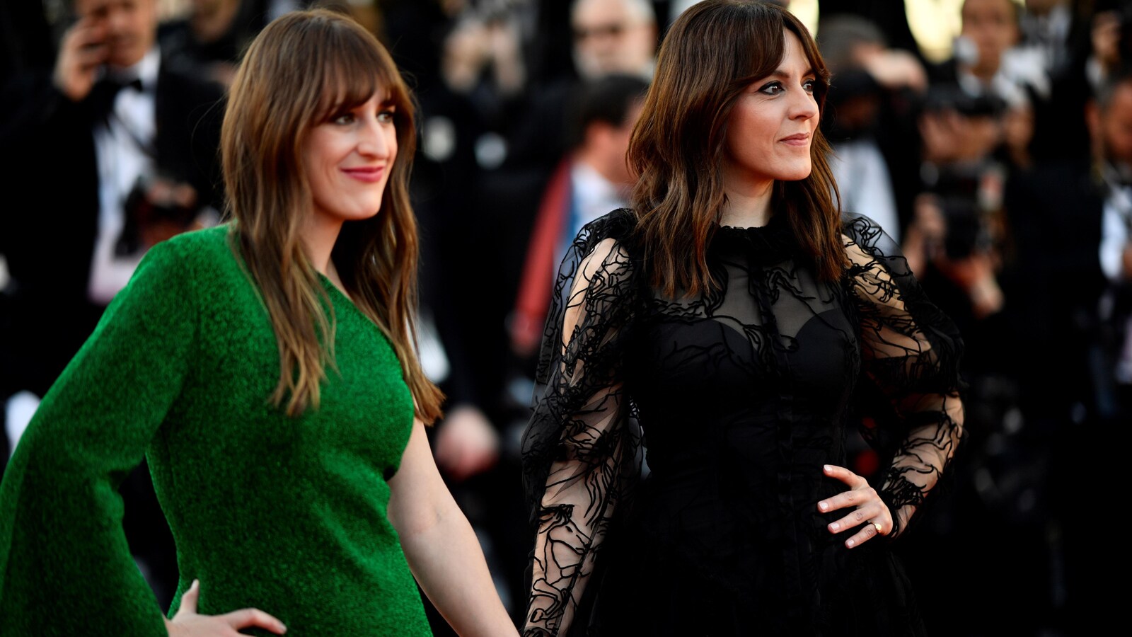 Les deux femmes habillées d'une robe verte et noire sourient.