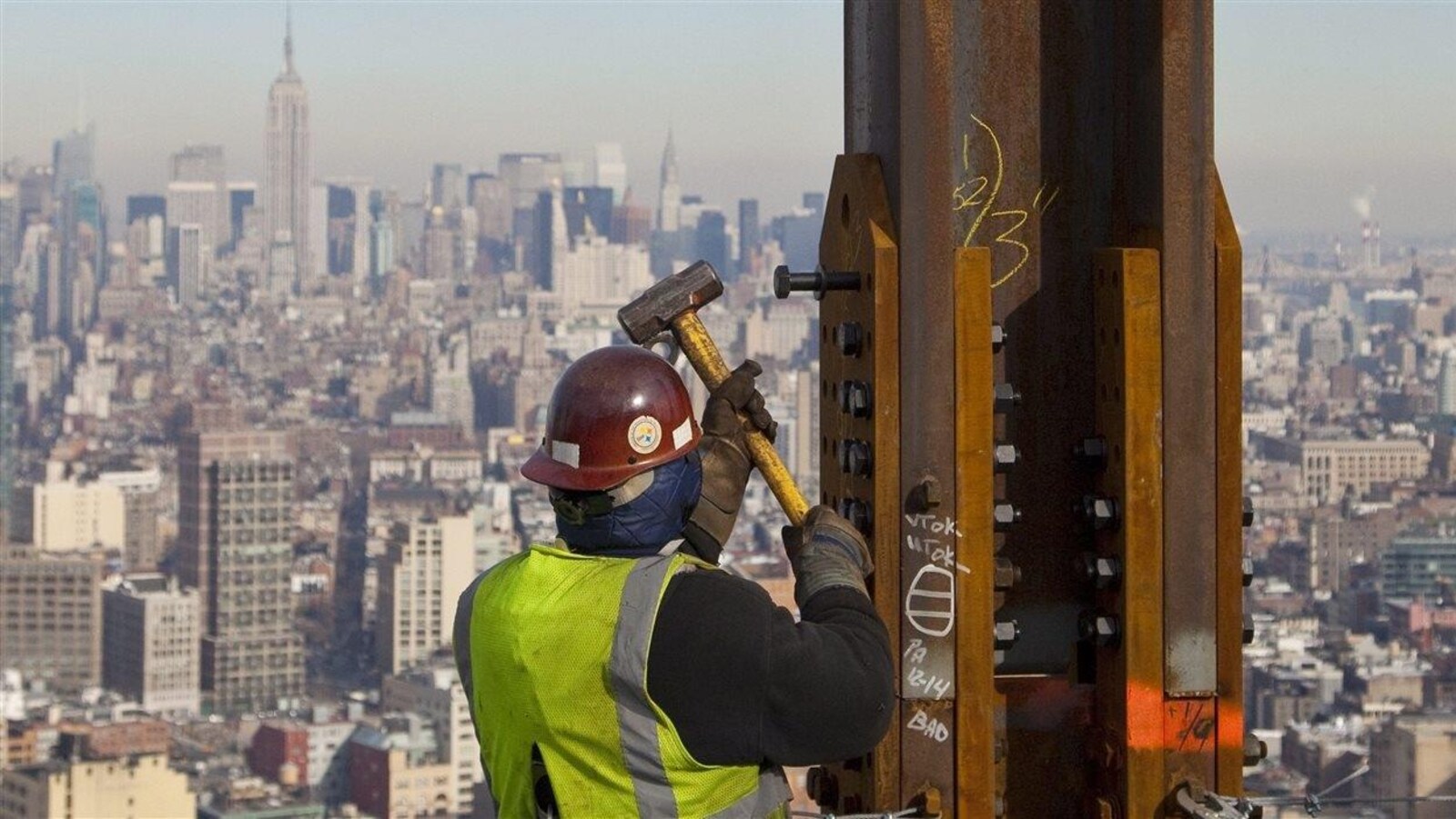 Le 16 décembre 2010, un charpentier de l'acier assemble des poutres au One World Trade Center à New York. En arrière-plan: l'Empire State Building.