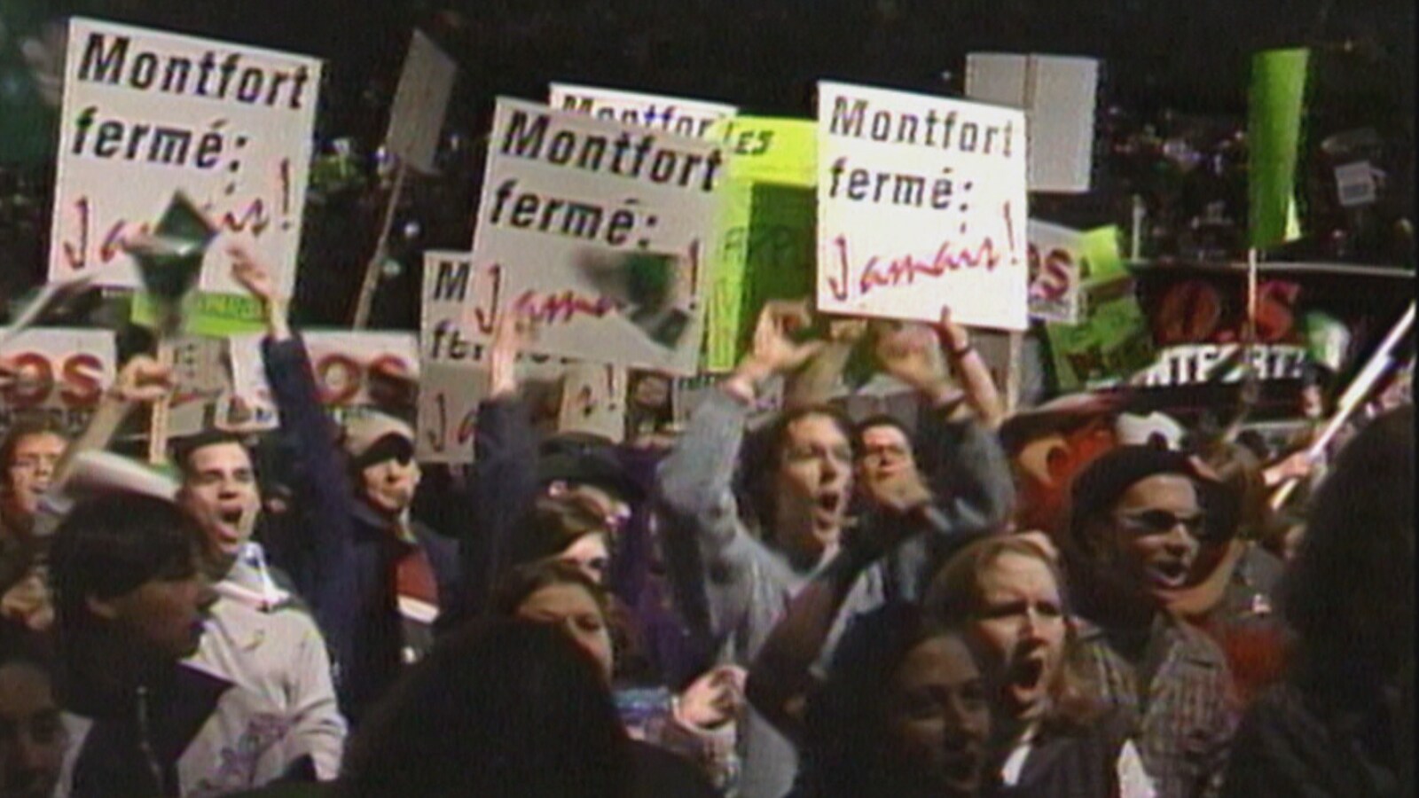 Des manifestants hurlant et brandissant des panneaux.