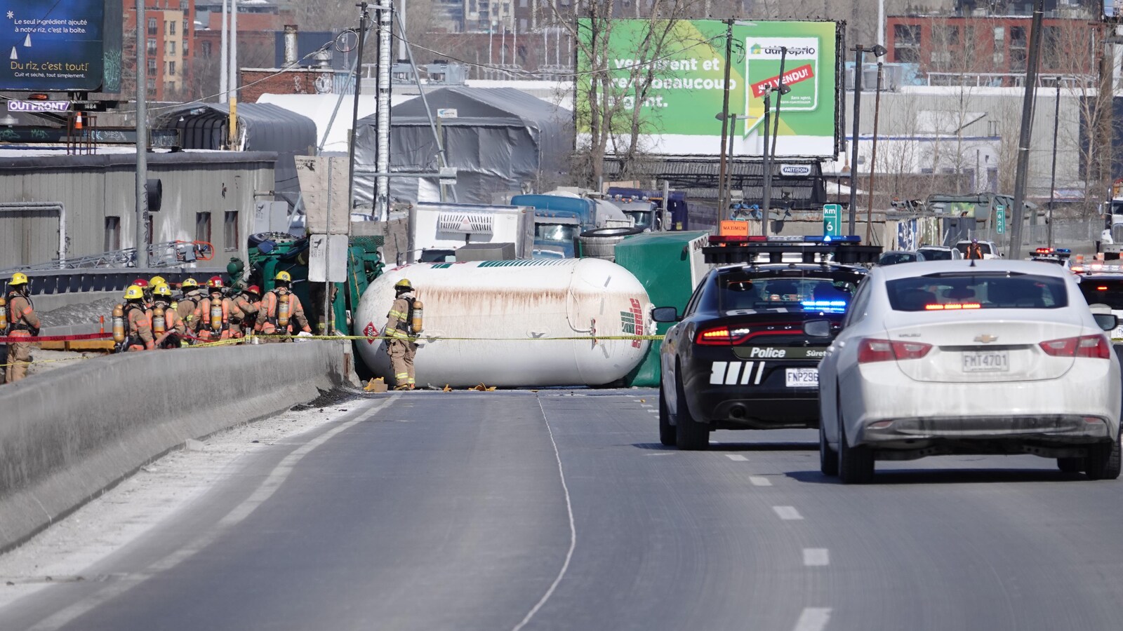 Des pompiers se tiennent près du camion renversé.