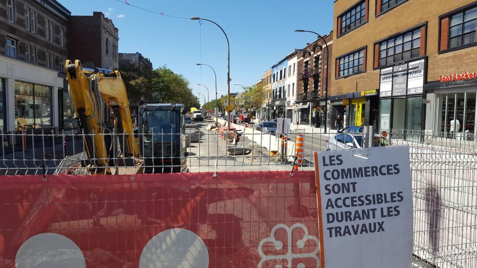 « Les commerces sont accessibles durant les travaux », peut-on lire sur une pancarte accrochée sur une clôture entourant un chantier.