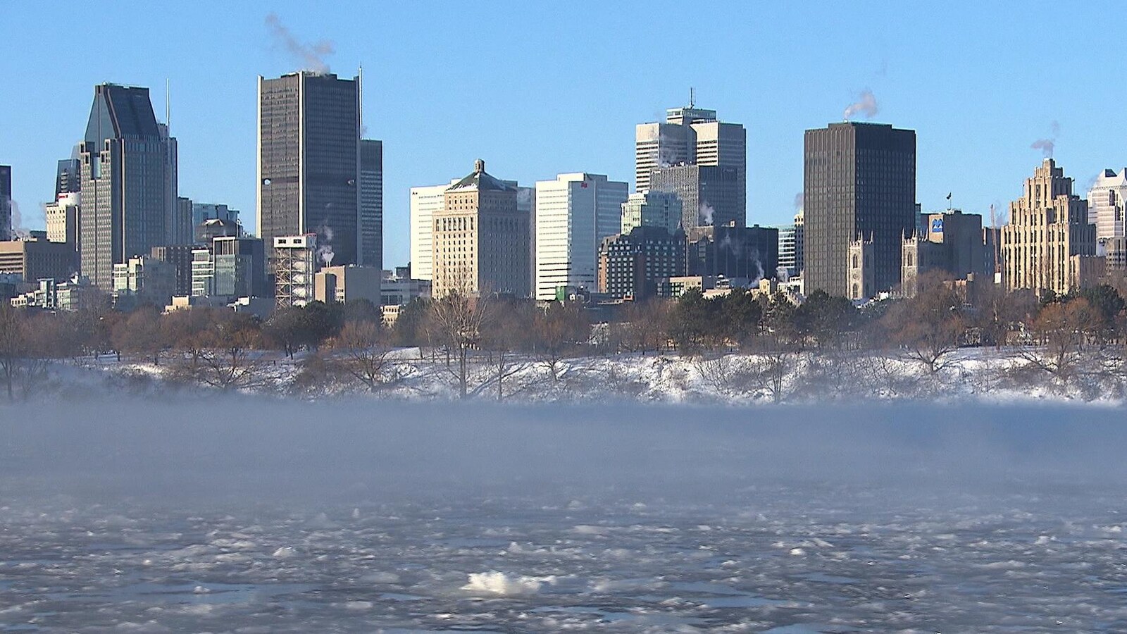 De la fumée s'échappe du fleuve Saint-Laurent avec des immeubles montréalais en arrière-plan.