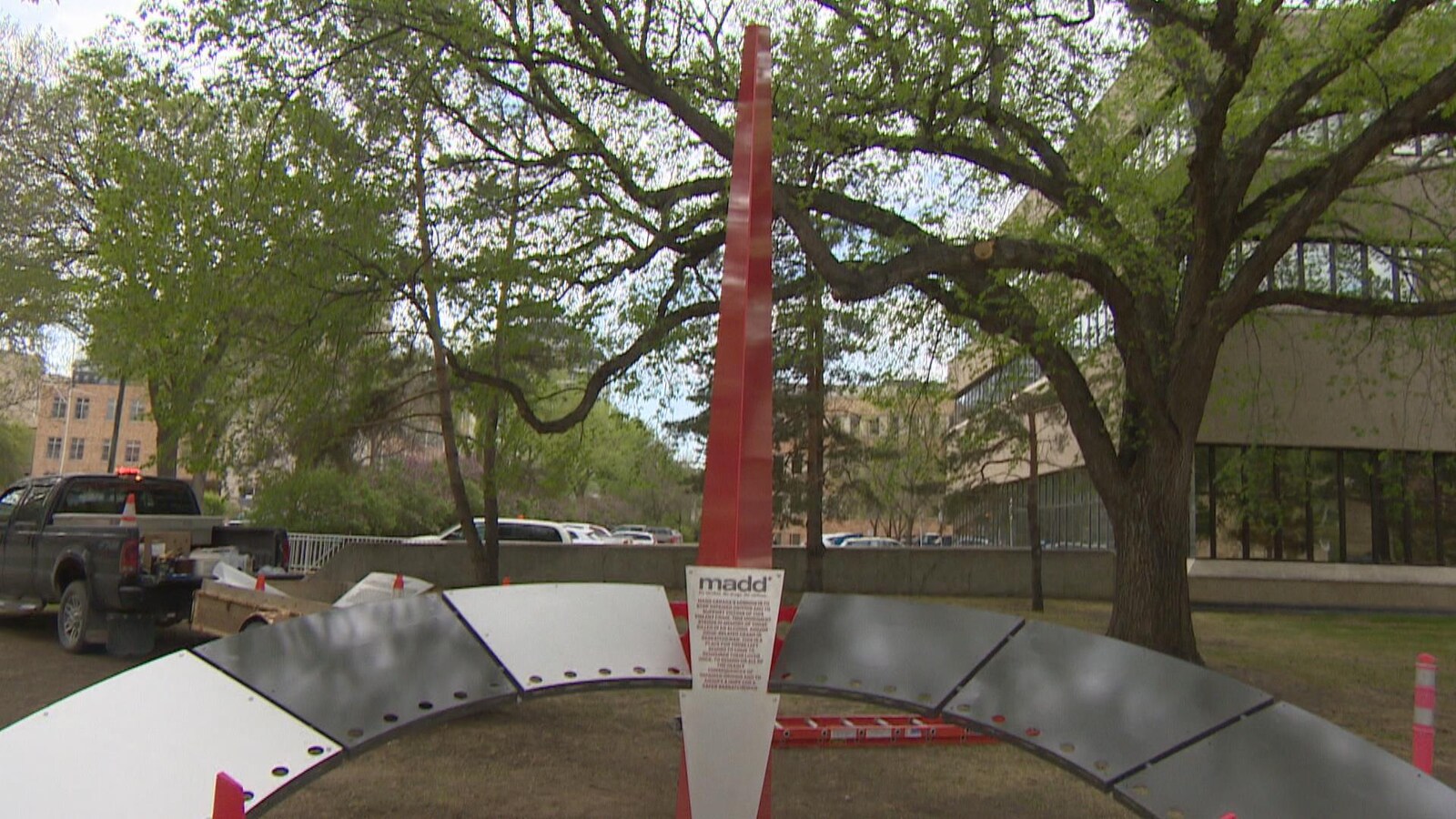Vue du monument à la mémoire des victimes. Une barre avec à sa base un arc de cercle en métal. Une plaque métallique au milieu porte sur laquelle est inscrit le sigle MADD suivi de la liste de 45 noms de victimes.