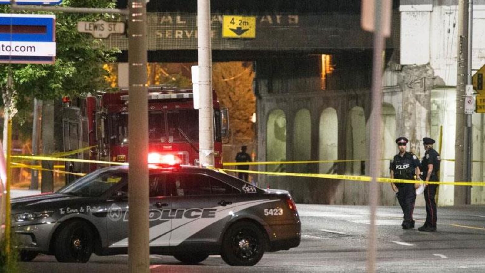 Une voiture de police et deux policiers dans une rue la nuit