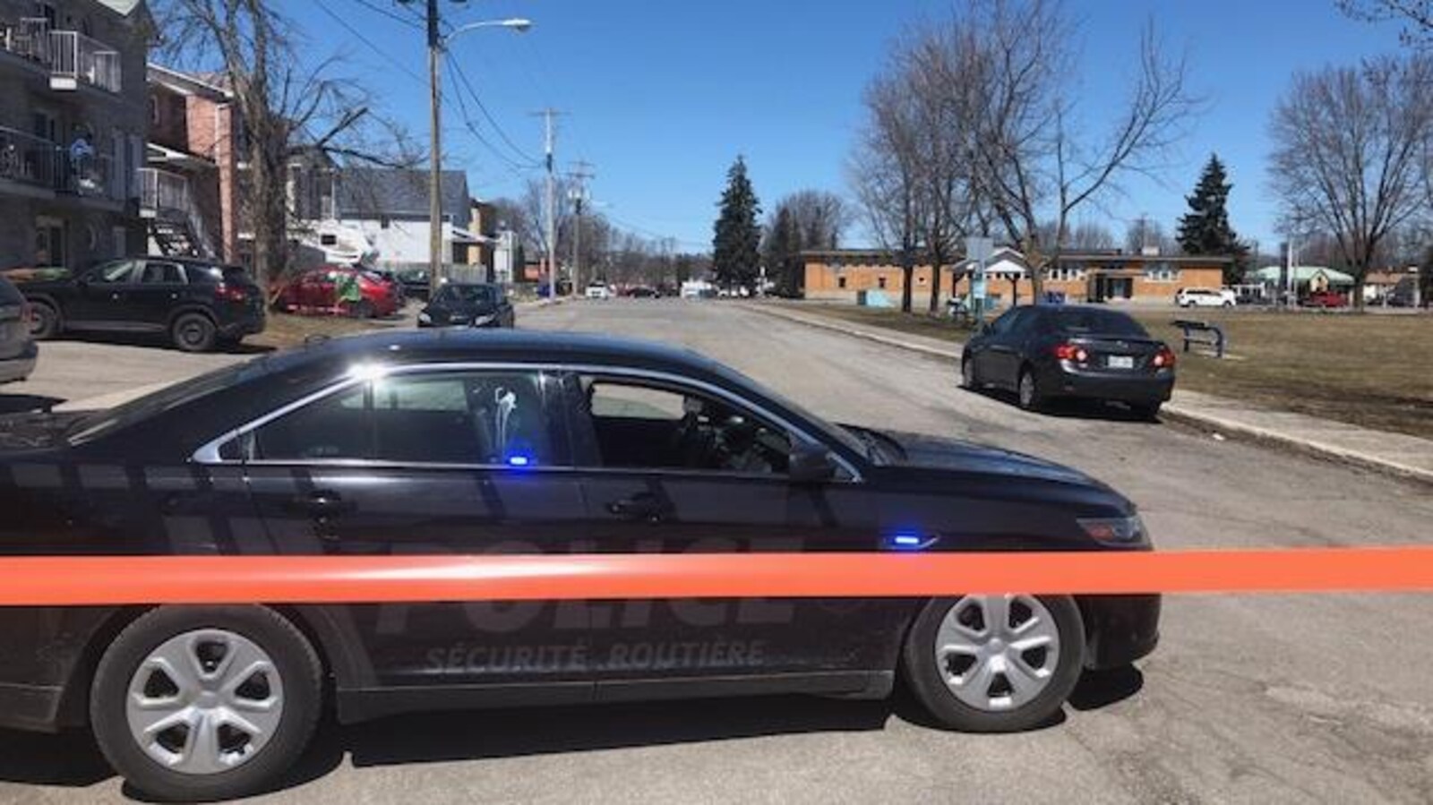 Une voiture noire du Service de police de Gatineau et un périmètre de sécurité qui ferme une rue.