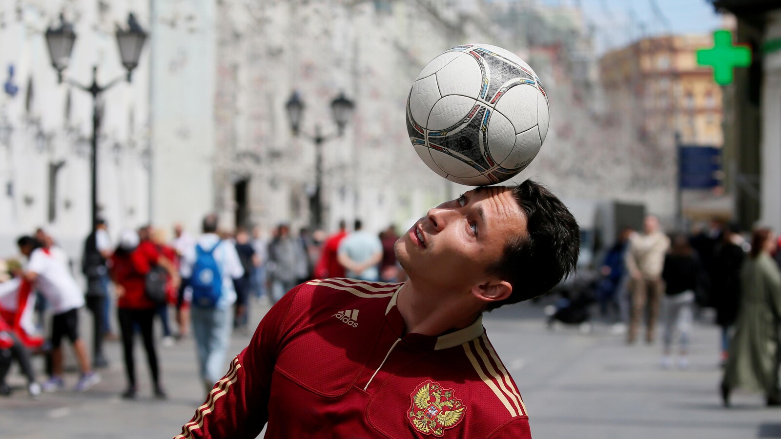 Un homme vêtu du maillot de la Russie s'exerce avec un ballon de soccer dans les rues de Moscou.