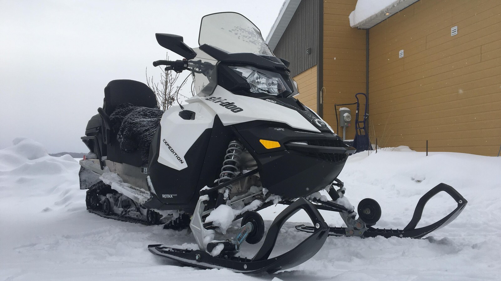 Une motoneige Ski Doo est stationnée près d'un bâtiment.
