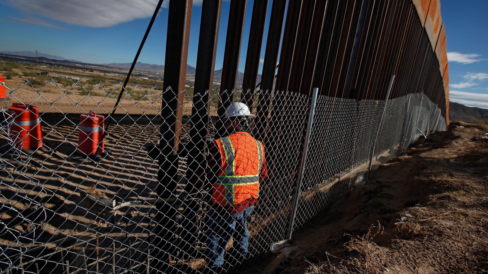 Un homme travaille à la construction d'un mur à la frontière entre les États-Unis et le Mexique.