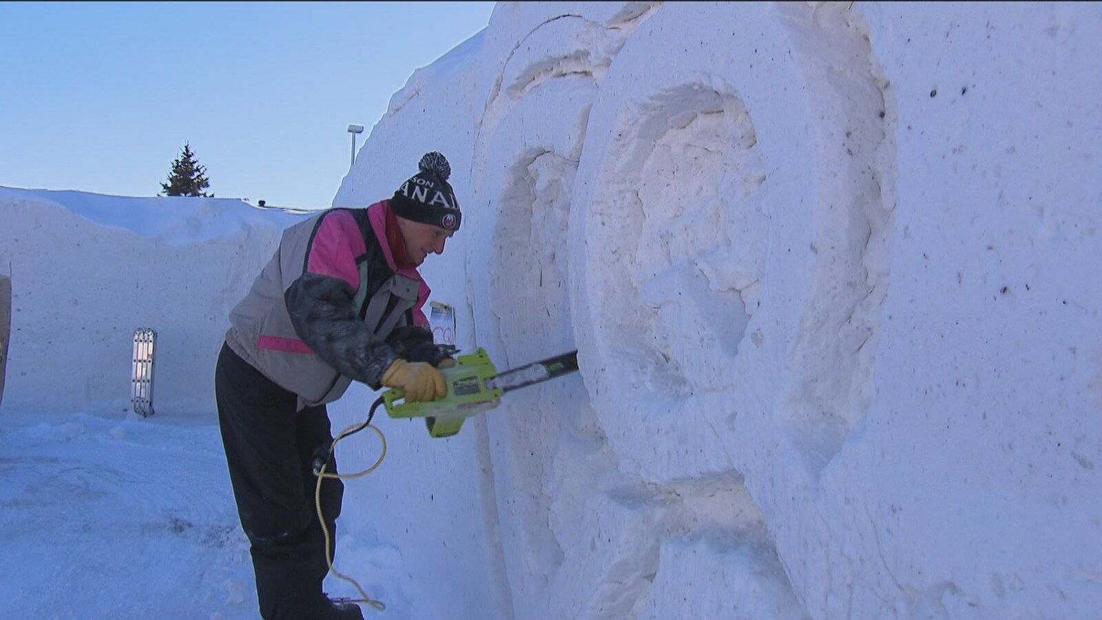 Un homme sculpte la neige à l'aide d'une scie à chaîne