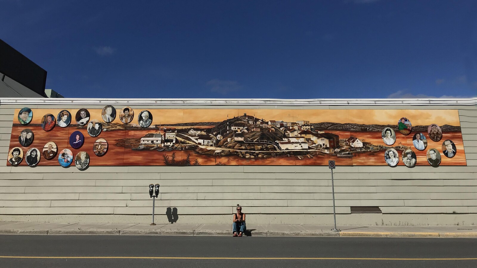 L'artiste Diane Boudreau est assise sur le trottoir devant son oeuvre.