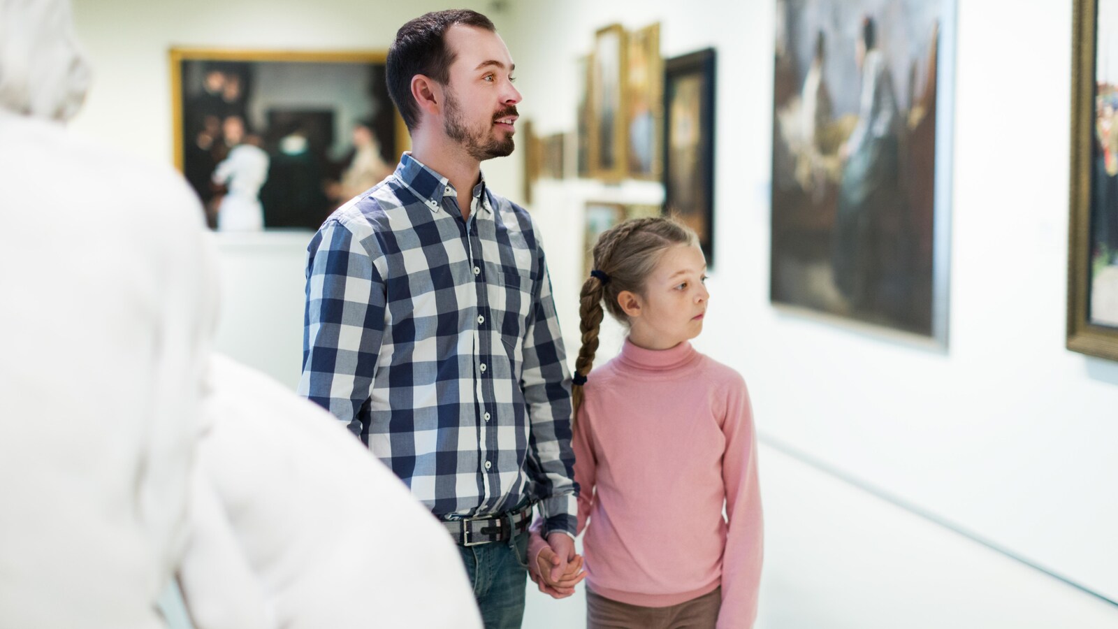 Un père et sa fille regardent un tableau au musée.