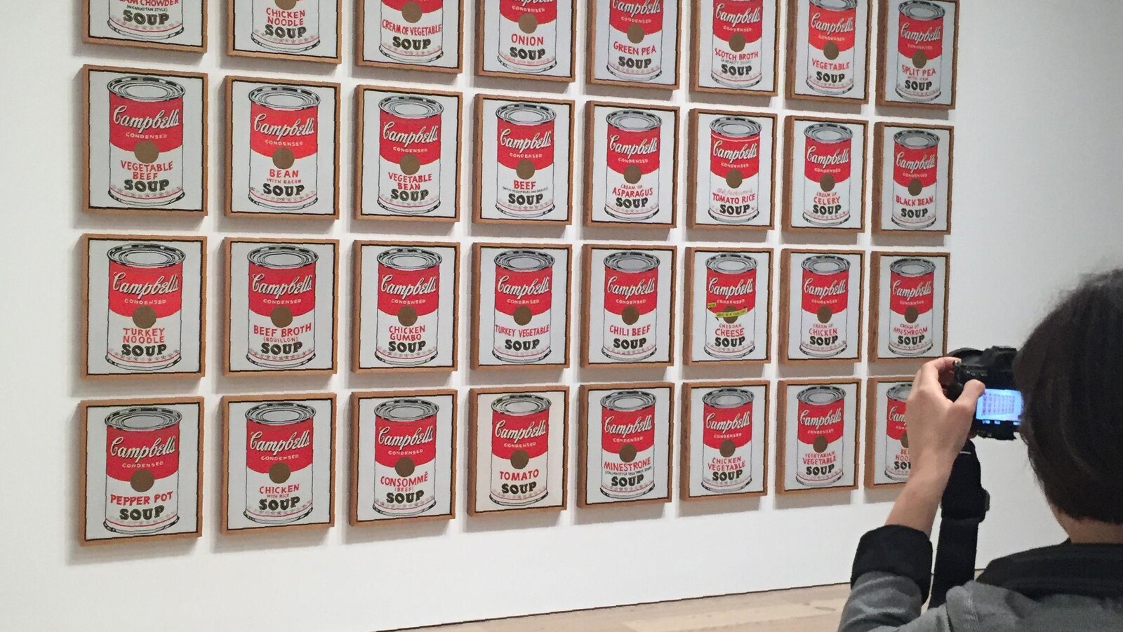 Sur le mur on voit des images des boîtes de soupe Campbell.