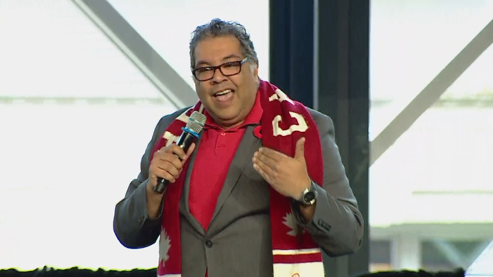 Naheed Nenshi, avec un foulard de l'équipe olympique canadienne au coup, s'adresse aux centaines de personnes présentes dans la salle.