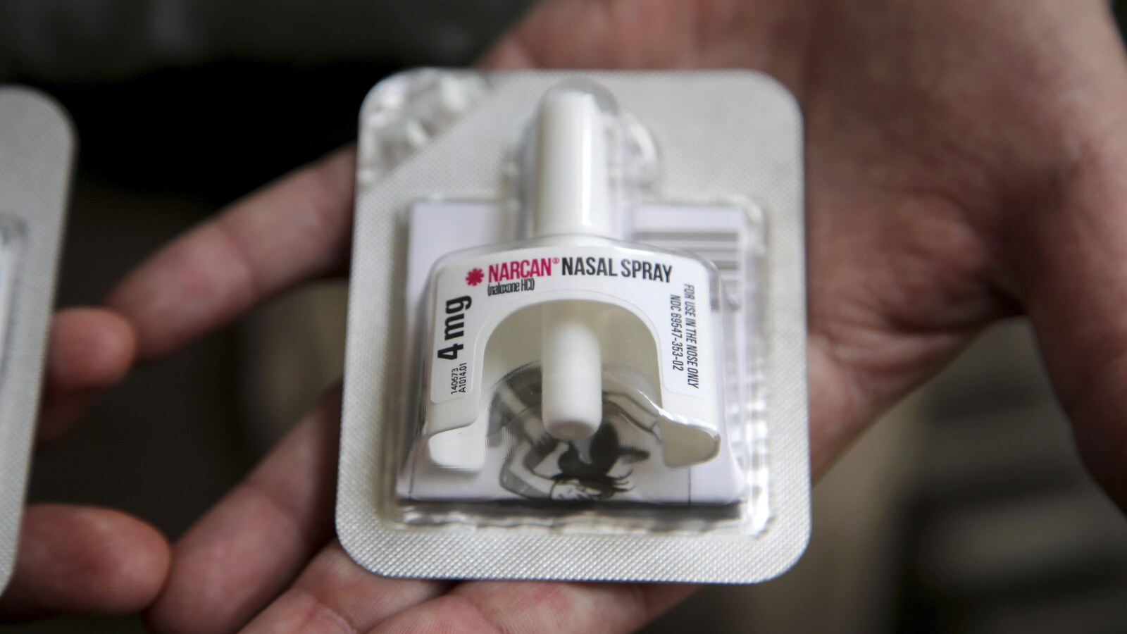 Une main ouverte présente un emballage de naloxone en vaporisateur