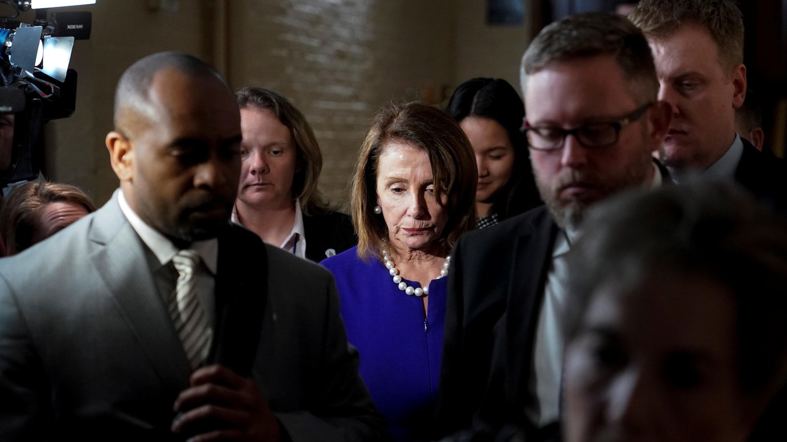 La démocrate Nancy Pelosi sort d'un caucus de son parti à Washington, entourée de plusieurs personnes.