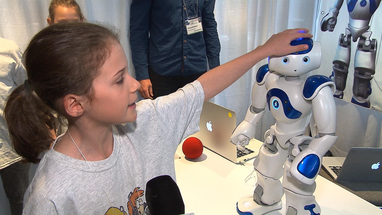 Une enfant caresse la tête du robot Nao