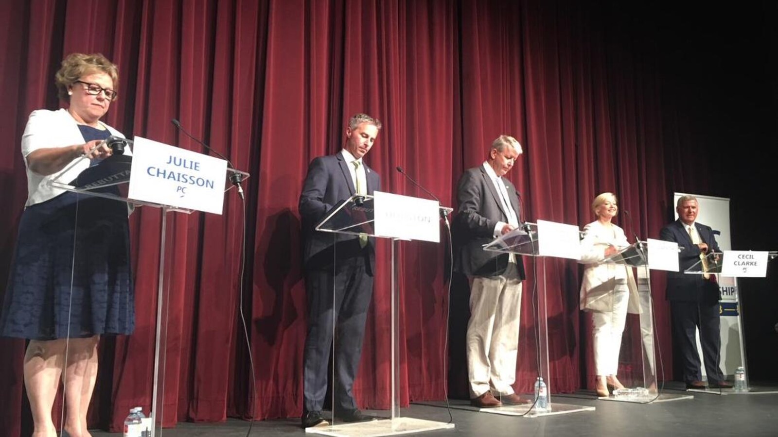 Les cinq candidats à la direction sont chacun à leur podium sur une scène, lors d'un forum, à Tusket.