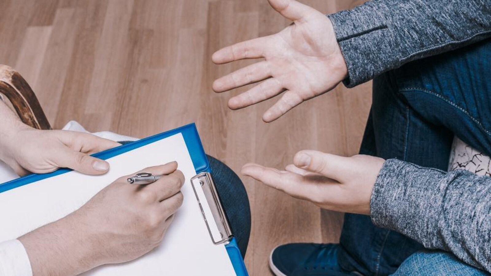 Un médecin prend des notes en présence d'un patient, assis en face de lui.
