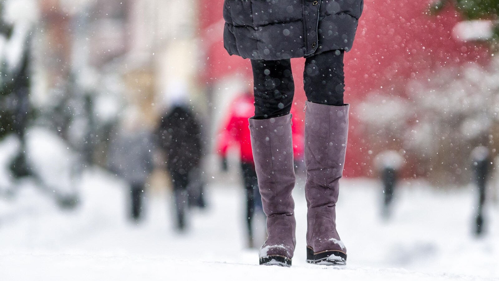 Gros plan sur les bottes d'une femme durant des chutes de neige.