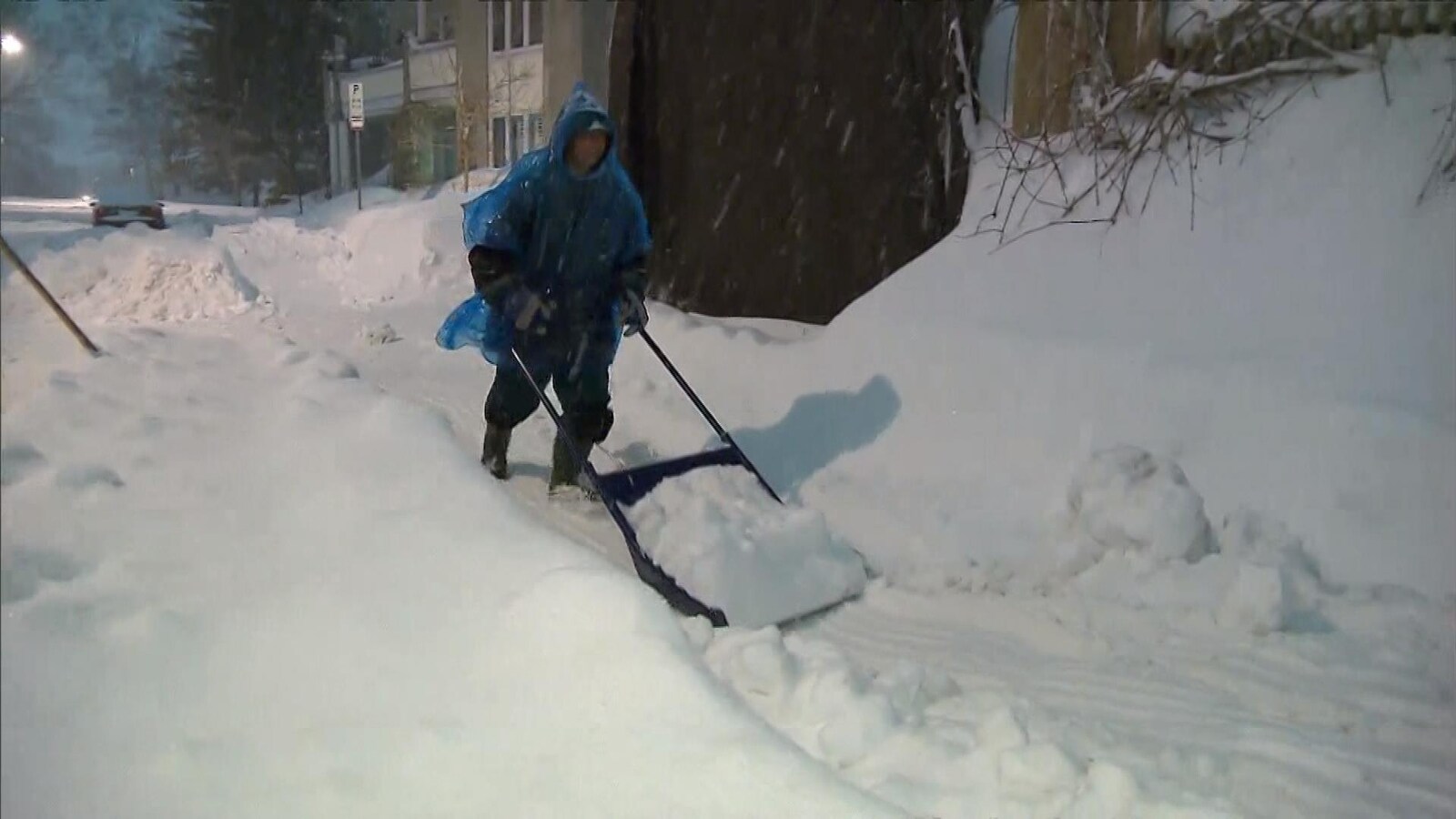 Une résidente pellette de la neige lors d'une tempête.