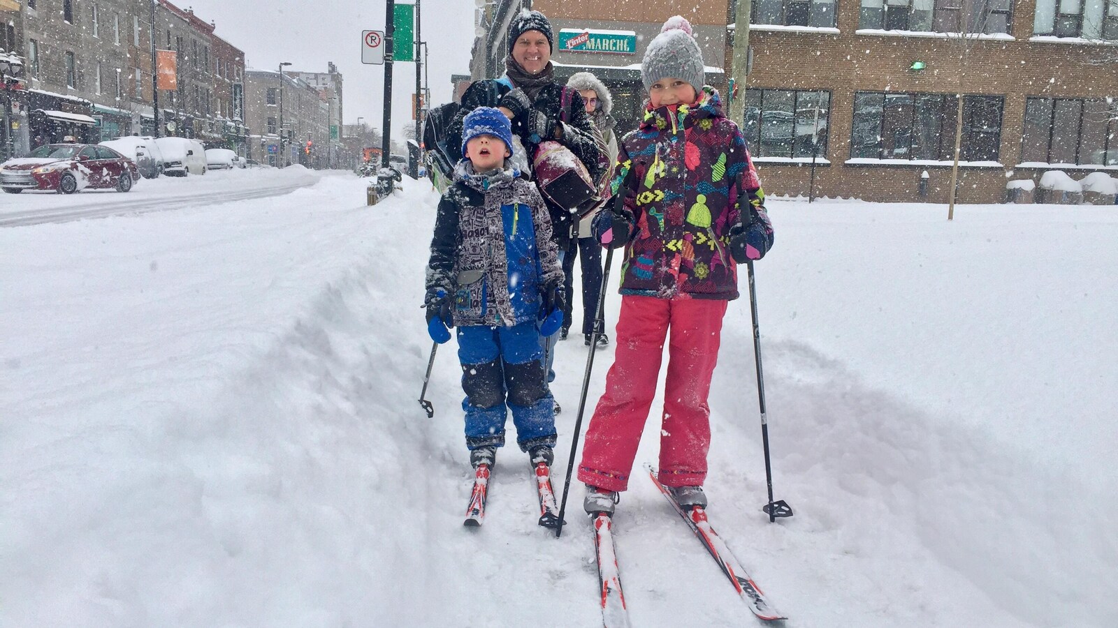 Des enfants font du ski de fonds sur le trottoir.