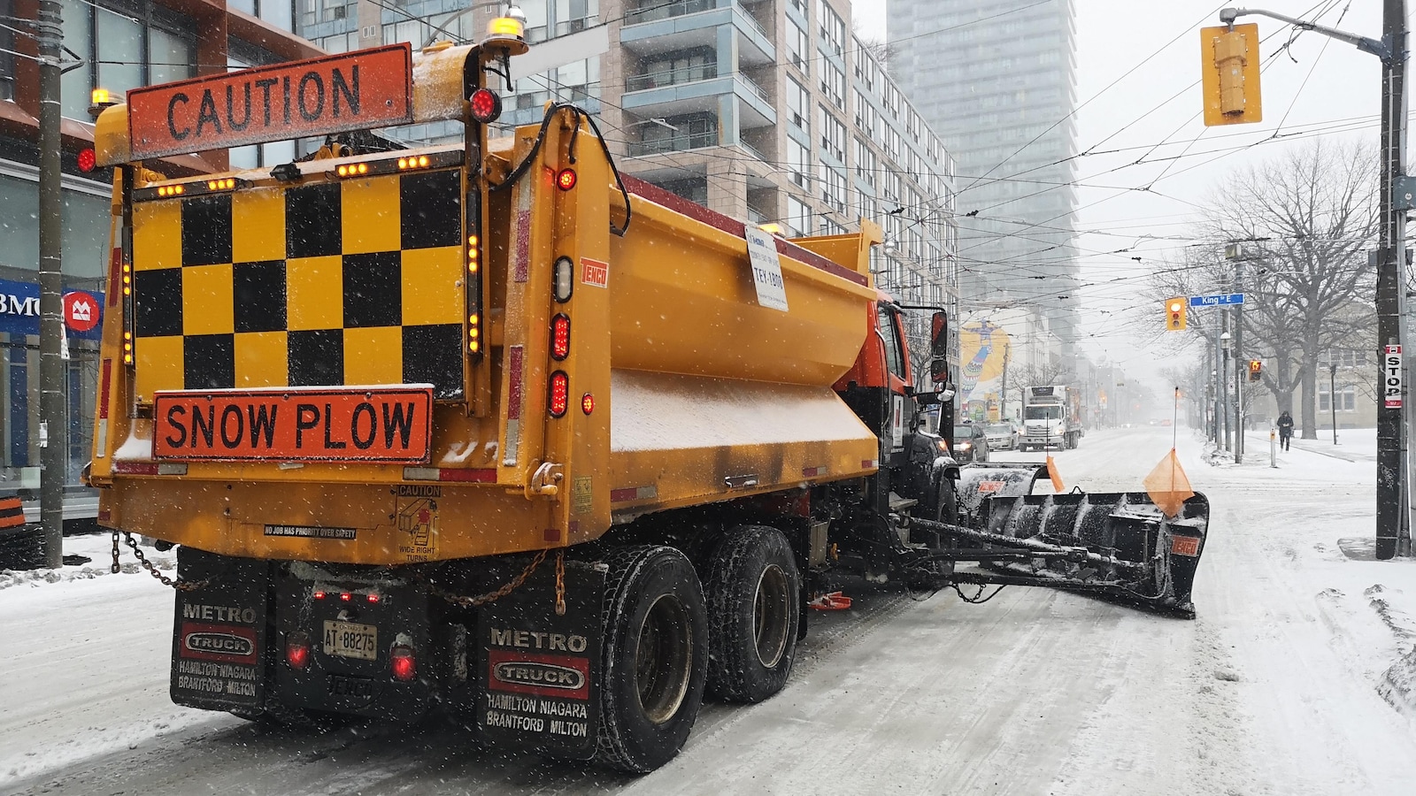 Photo d'un camion de déneigement jaune dans une rue enneigée