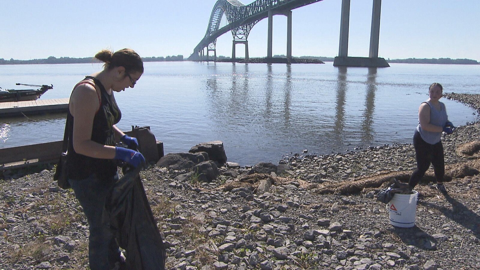 Deux citoyennes ramassent des déchets sur le bord du fleuve Saint-Laurent, sous le pont Laviolette.