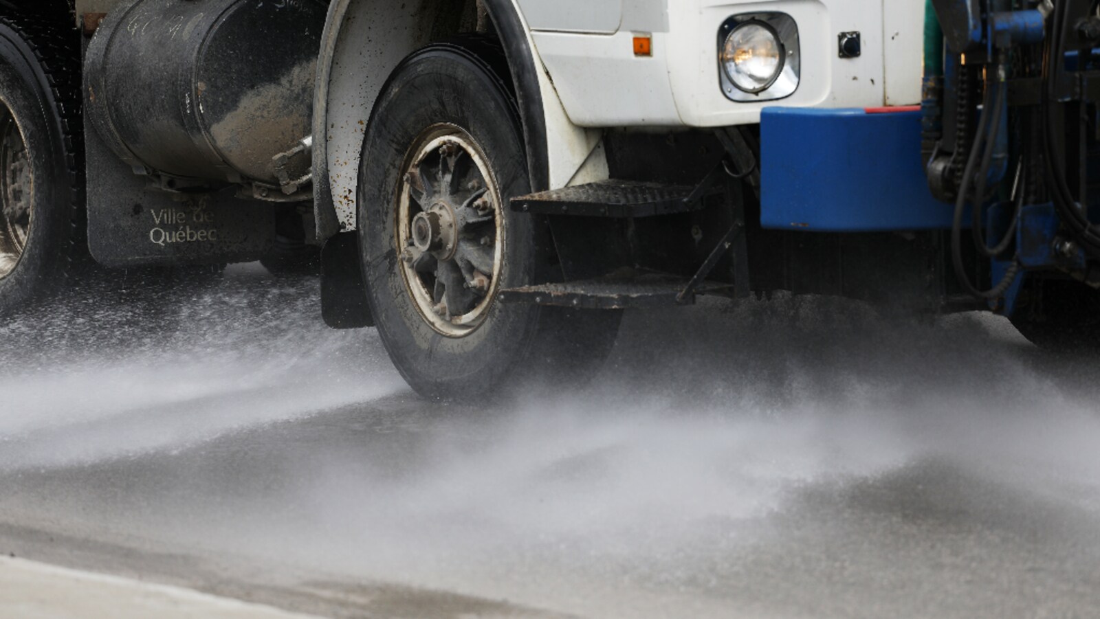 Un camion de la voirie projette un jet d'eau le long d'une rue.