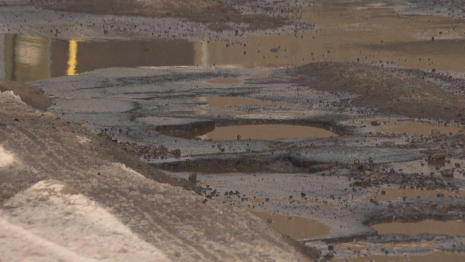 Des nids-de-poule sur une chaussée couverte d'eau.