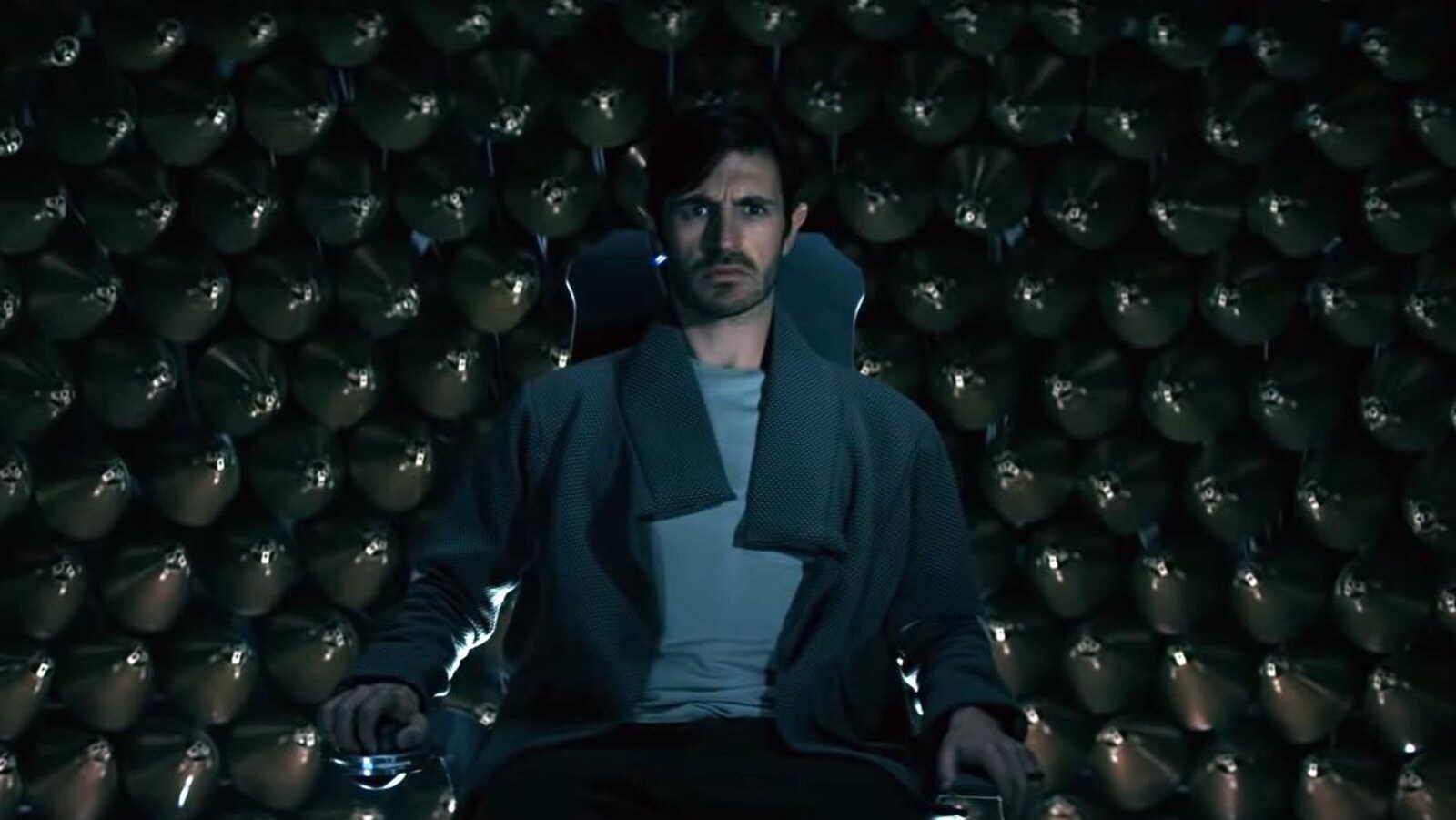 Un homme assis regarde devant lui, l'air inquiet, dans une scène de la série «Nightflyers».
