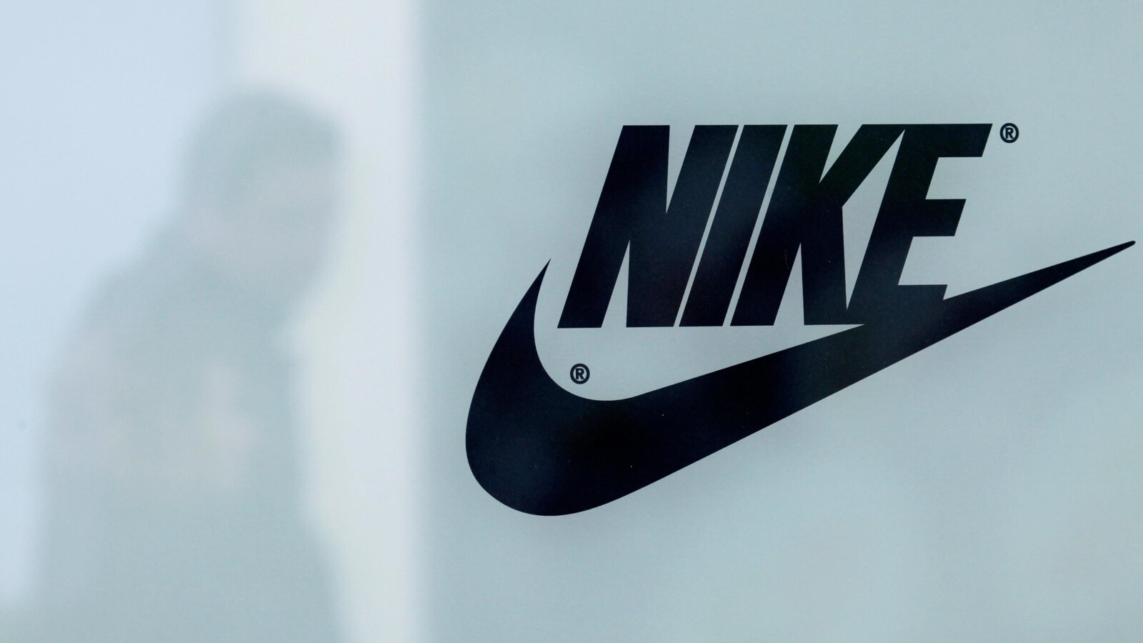 Un logo de Nike avec un homme passant derrière.