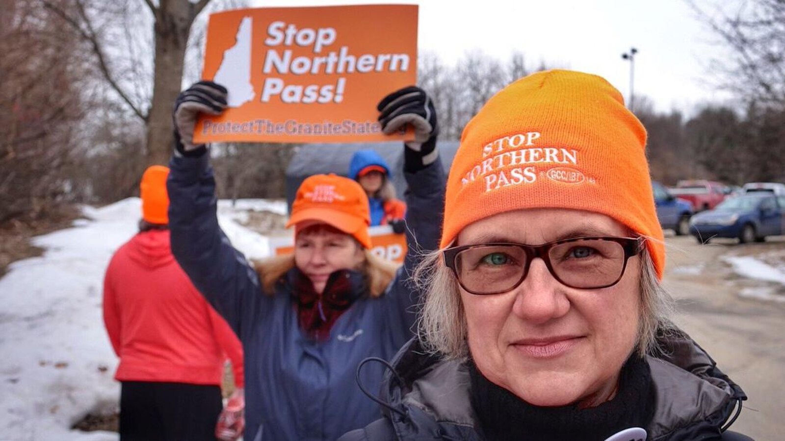 Deux militantes opposées au projet Northern Pass. L'une porte une tuque sur laquelle on peut lire « Stop Northern Pass », l'autre bandit une pancarte arborant le même message.