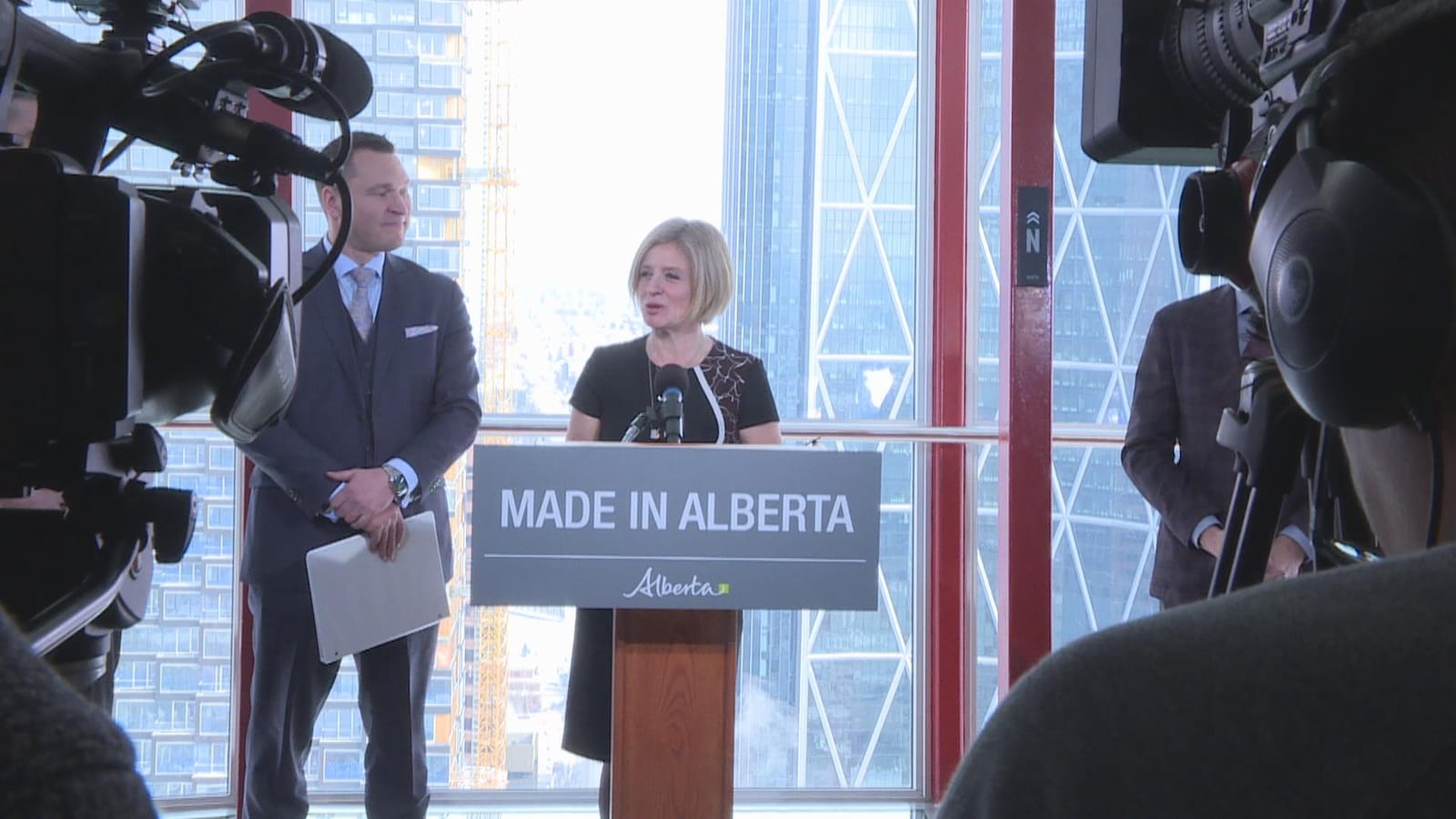 La première ministre Rachel Notley aux côtés du ministre du Développement économique et du Commerce de l'Alberta, Deron Bilous, devant des caméras au dernier étage de la Tour Calgary.