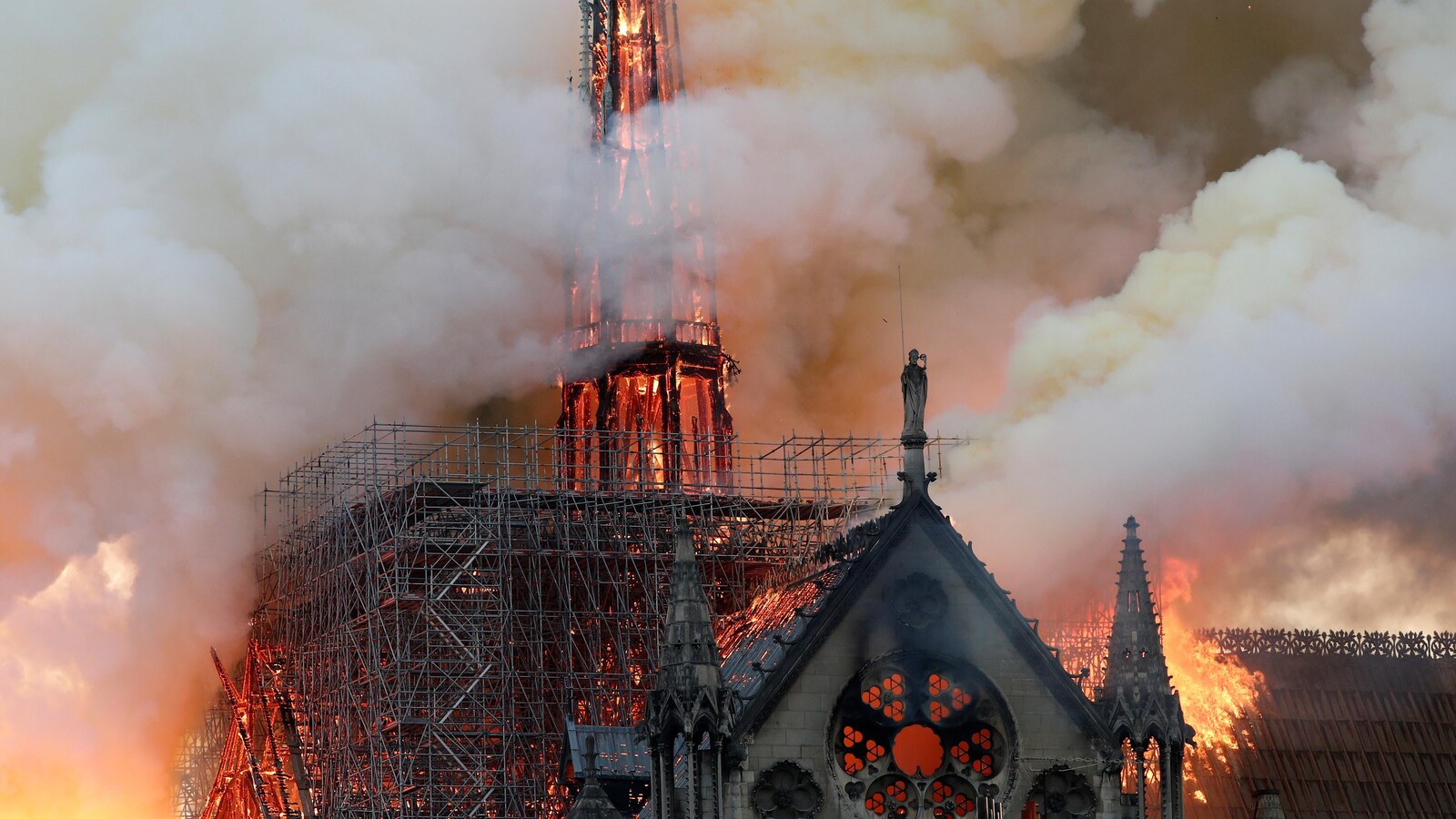 La flèche et des échafauds sur le toit de la cathédrale Notre-Dame de Paris sont en feu entourés de colonnes de fumée.