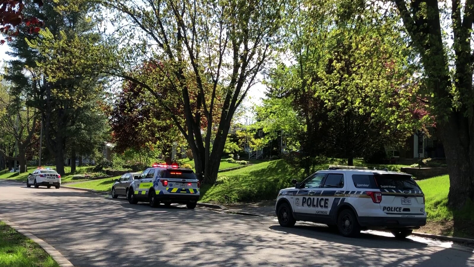 Des voitures de police et de premiers secours stationnées devant une résidence.