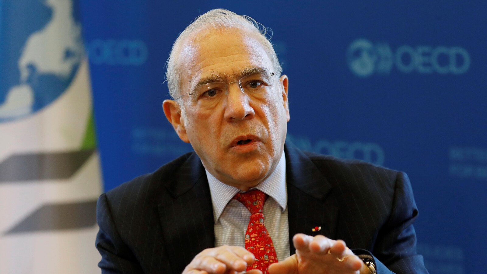 Angel Gurria, les mains levées à la hauteur de la poitrine, regardant devant lui