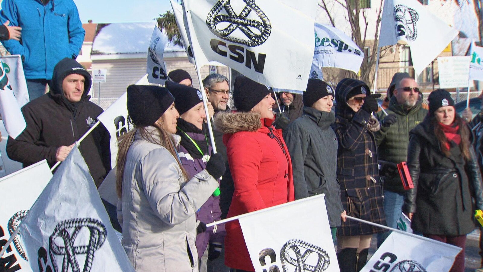 Des personnes rassemblées dehors avec des drapeaux de la CSN.