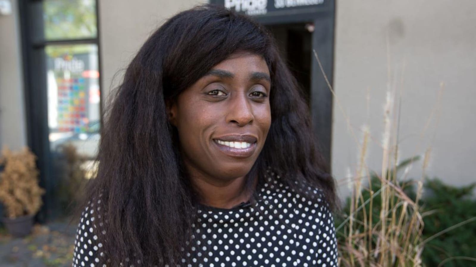 Photo d'une femme noire aux cheveux longs à l'extérieur d'un édifice