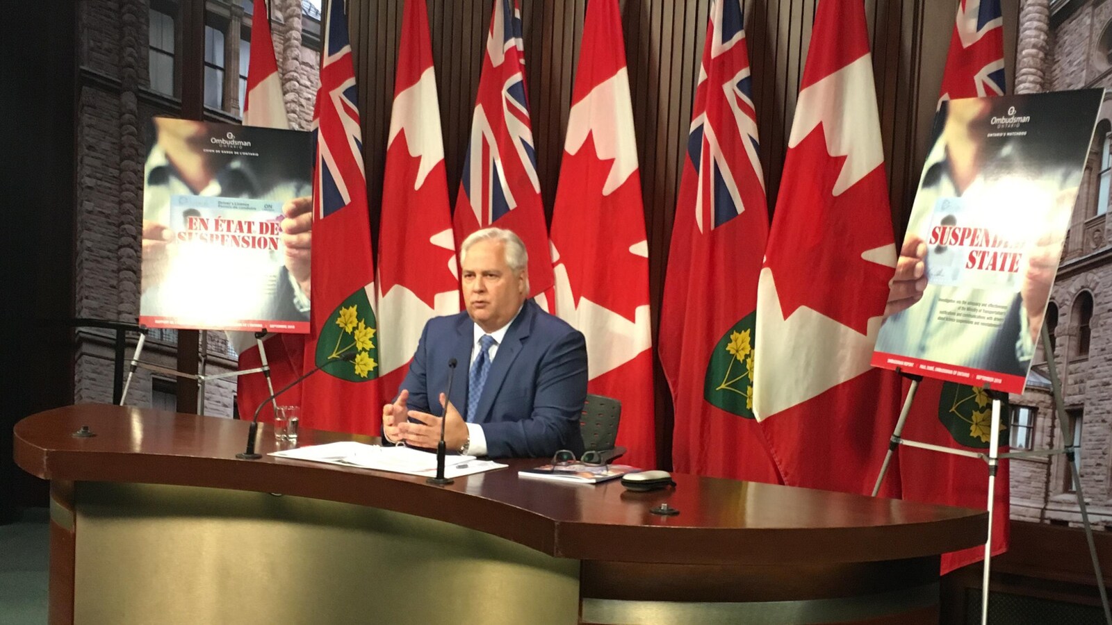 Photo d'un homme assis derrière une table à un point de presse