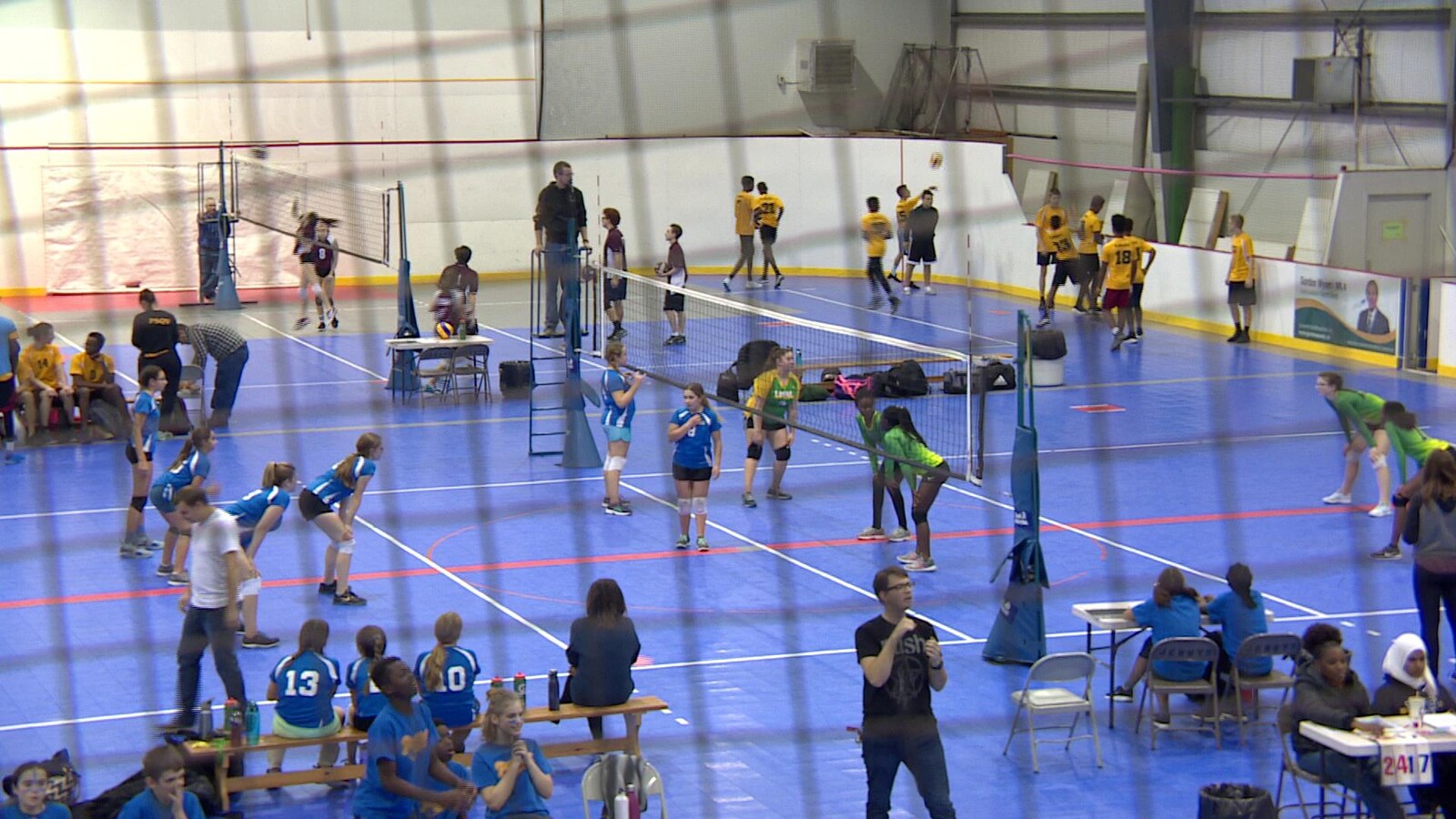 Vue de plusieurs terrains de volleyball où jouent des dizaines de jeunes.