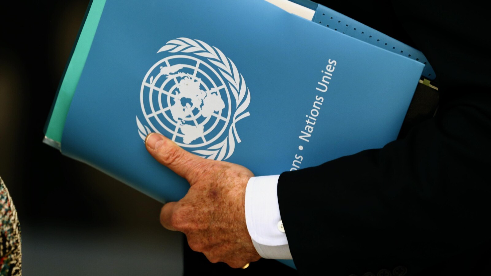 Un homme tient un classeur portant le logo de l'ONU.